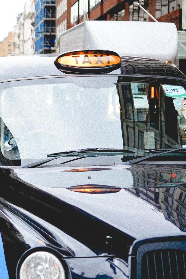 man talking through taxi car mirror during daytime