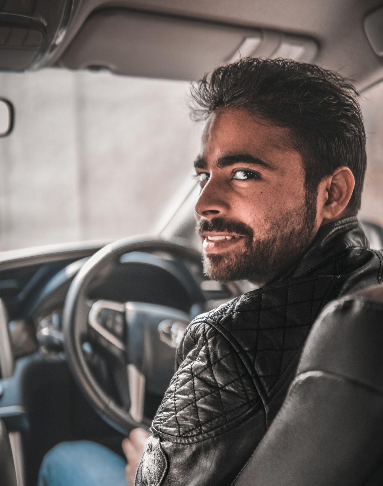 man in black leather jacket sitting on blue car seat